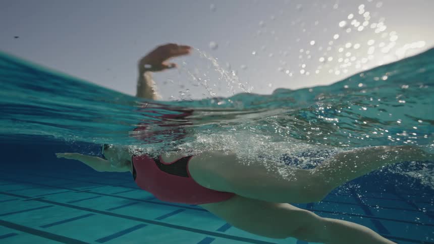 Split level shot of a woman in a swimming pool