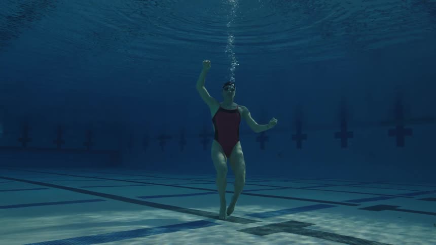 A woman floats to the bottom of a large swimming pool