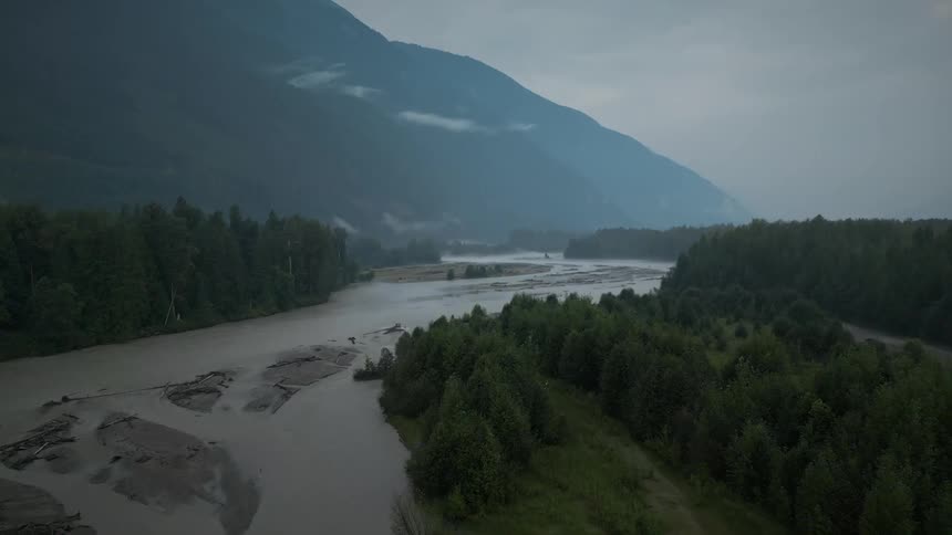 Aerial view of a river in the forest next to the mountain