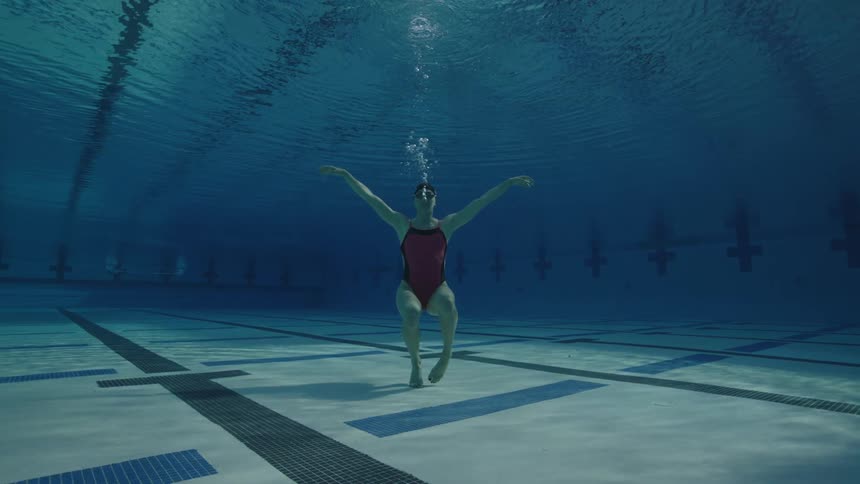 Swimmer stands on the bottom of an olympic swimmng pool