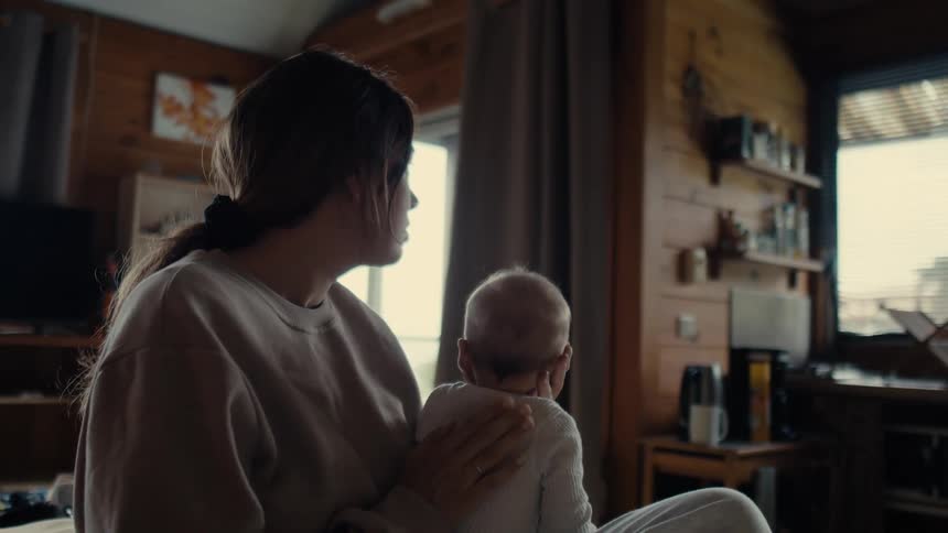 Mother sits with her baby in the living room at home