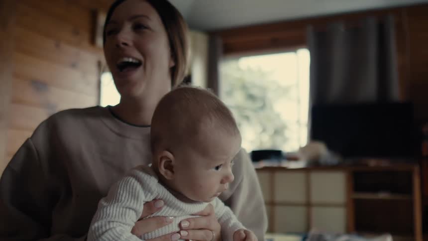 Mother holding her baby son in her arms as he sneezes