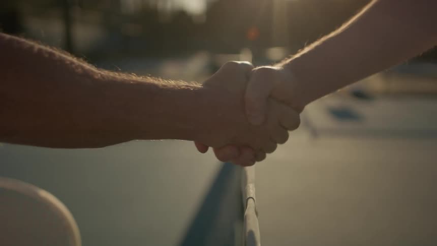 Tennis players standing on tennis court shake hands over the net