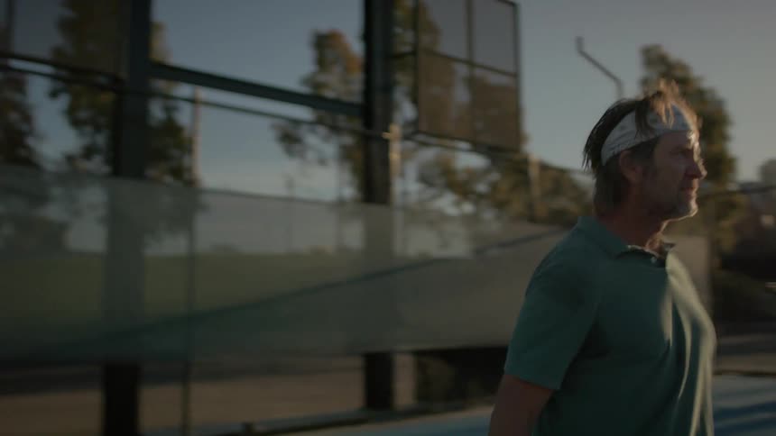 Man playing tennis on a court at sunset
