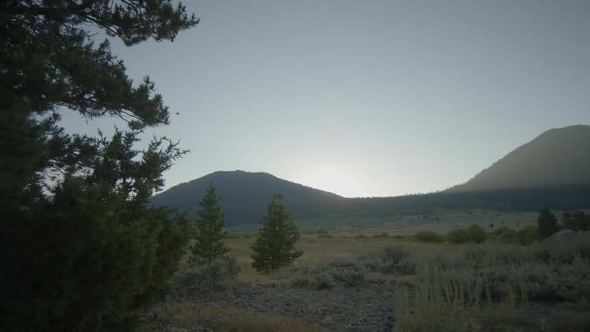 A green field leads to a mountain in the distance