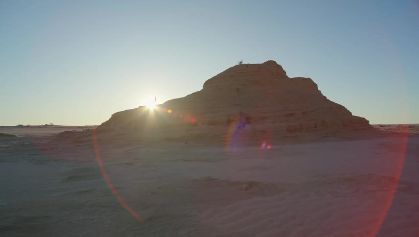 The sun hiding behind a rock formation in the desert