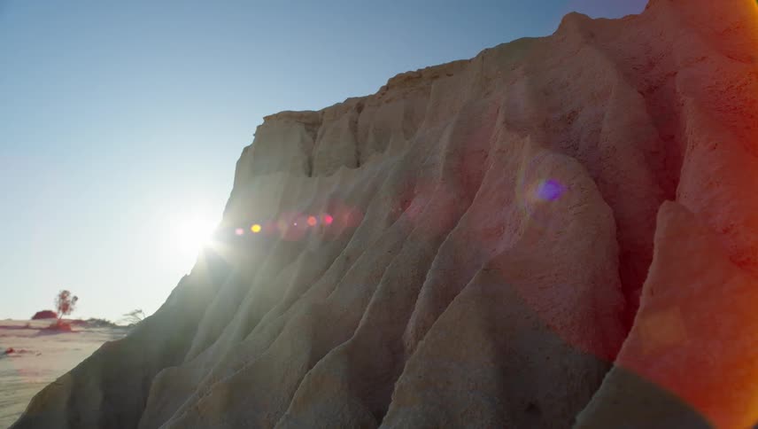 Sun shines behind a rock formation in the desert