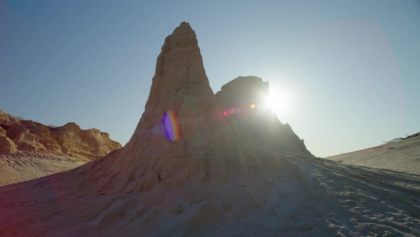 Sun shines behind a rock formation in the desert
