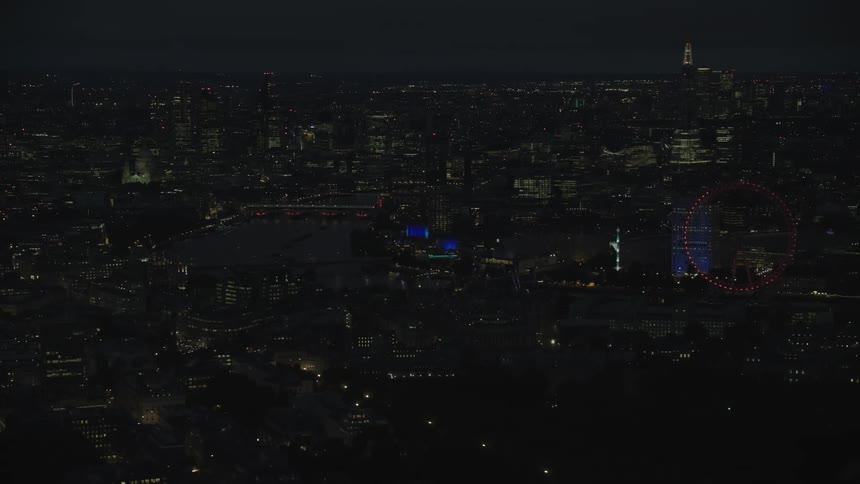 Aerial view of illuminated buildings and a ferris wheel at night in the city