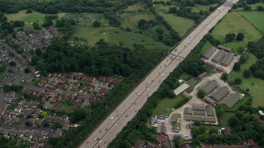 A large highway crossing a country field and a suburban town