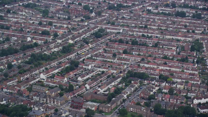 Crowded neighborhoods of row houses and apartments close together as traffic moves on the streets