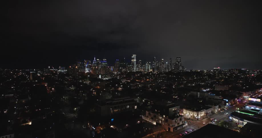 Aerial of the city illuminated at night with a cloudy sky