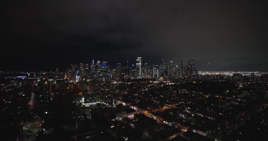 Aerial of a metropolitan region with many tall buildings at night