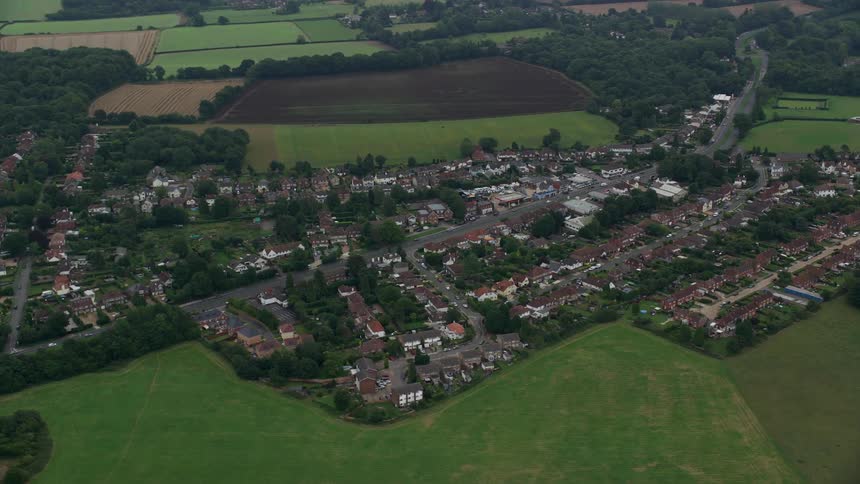 Aerial view of a small village surrounded by green fields and trees