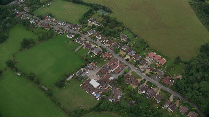 A cluster of residential homes line a street that is located far away from a city