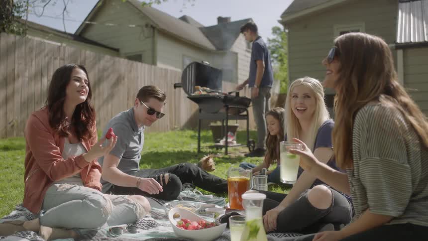 People sit down to a barbecue in their yard