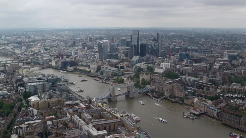 Tall buildings overlook the city as traffic moves along the coast and boats sail under london bridge