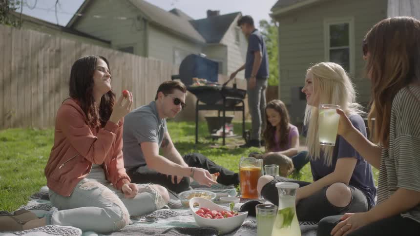 A group of people are having a barbecue in the backyard