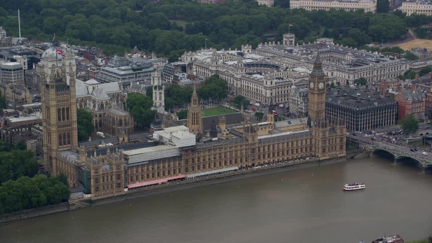The clocktower stands tall on the house of parliament along the north bank of the river thames in london as traffic moves across the bridge