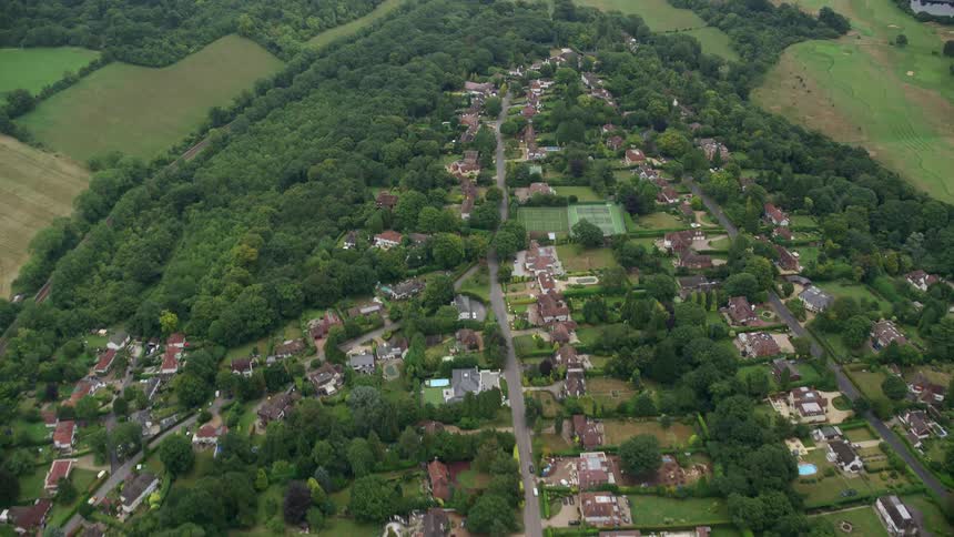 Aerial view of a residential area with lots of trees and green spaces arranged in a grid pattern with a park in the center