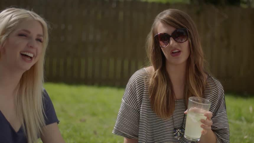 People are sitting on a blanket in the yard drinking lemonade