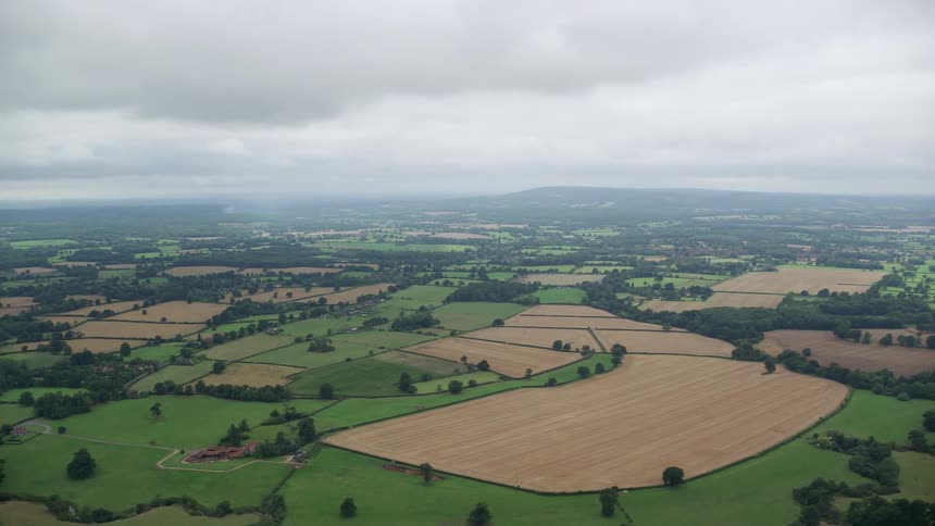 Rural countryside stretches to the hazy horizon under an overcast sky