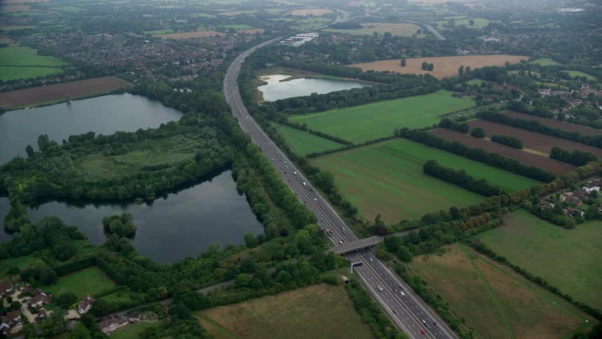 Traffic winds along highway passing ponds and residential neighborhoods