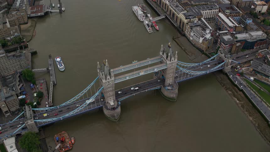 Road traffic crosses london bridge while watercraft move along the thames