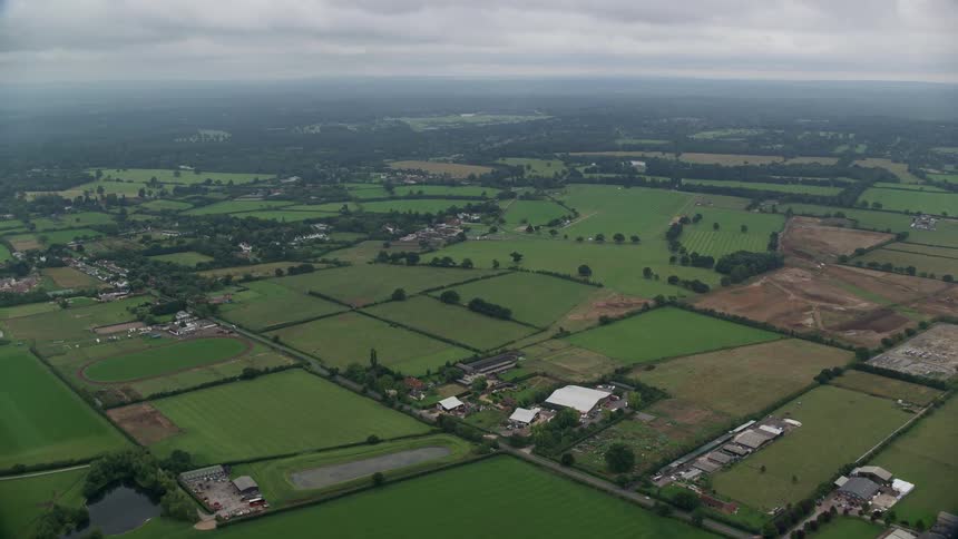 Several farms occupy area between forest and woods on foggy day