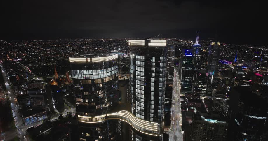 A city skyline at night with skyscraper buildings as light shines through buildings