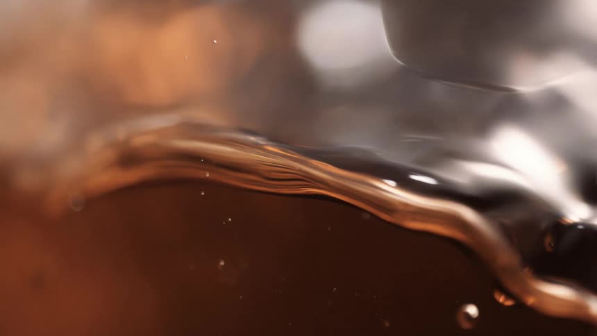 A clear brown liquid flowing in a glass container