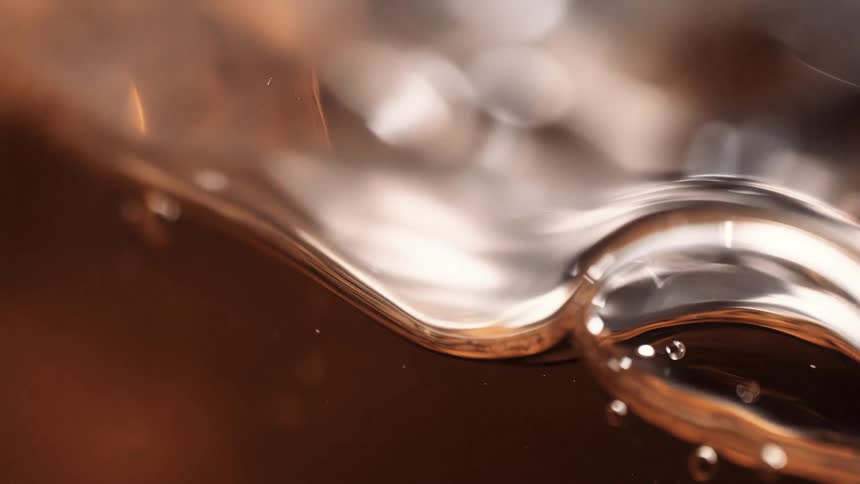 Dark amber beverage forms bubbles while glass is filled