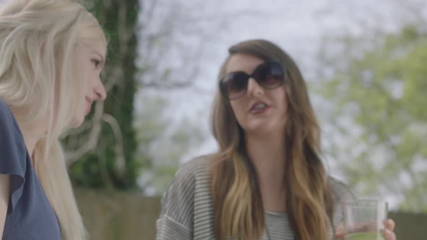 Women are talking and drinking in a yard