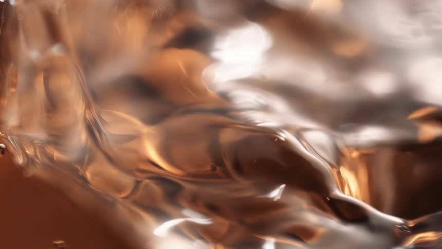 Amber beverage reflects the light while being poured into a glass