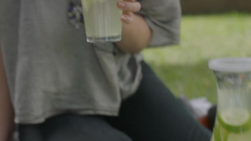 A woman picks up a glass of lemonade