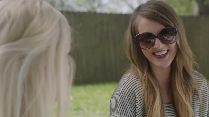 Women are in a yard talking on a sunny day