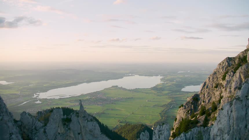 Aerial view of a mountain range with a landscape of fields and lakes on the horizon
