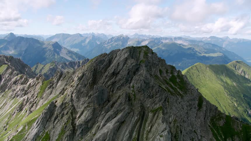 Moving over jagged rocky peaks to green ridges in a mountain range