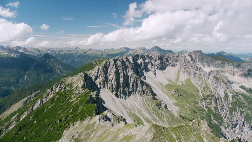 Mountain with rough edge slightly covered in green grass and snow
