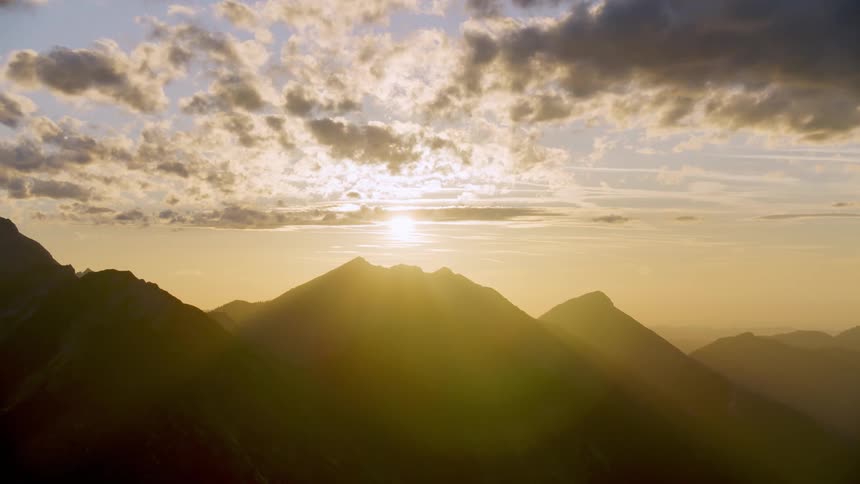 Golden sun shining on the silhouette of mountain peaks and ridges
