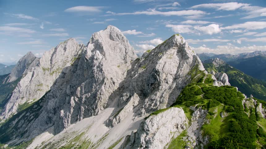 Rough mountain ridge with peaks high in a cloudy sky and mountains in the distance