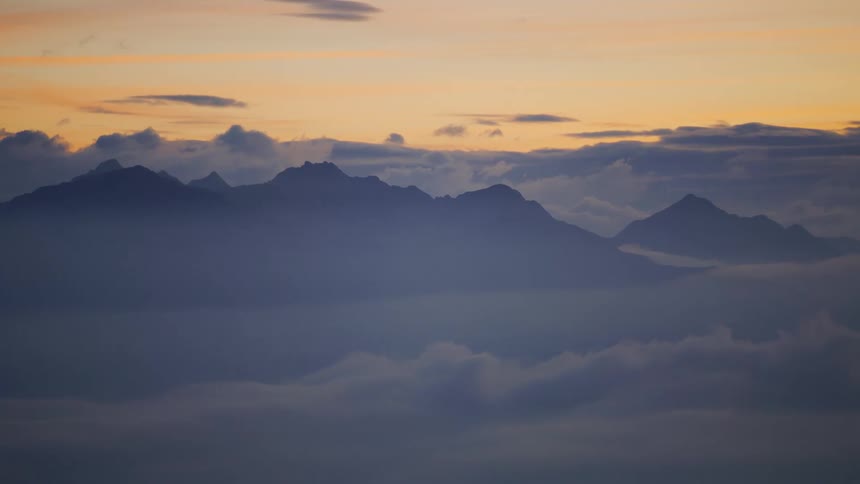 An aerial view of a mountain surrounded by thick clouds
