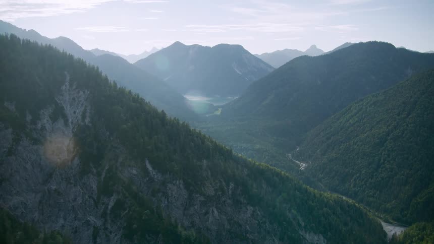 Beyond a forest there are series of mountains covered in grasses