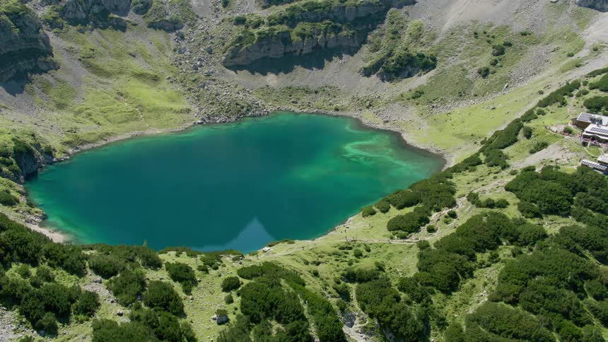 Houses on a hilltop overlook a blue lake in the mountain valley