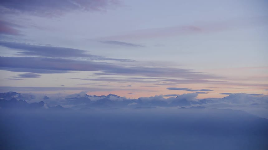 View from above as colors in the sky reflect on the clouds in the distance