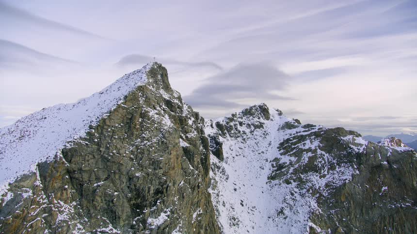 Mountains with snow on top and behind another region of mountains where the sun shines