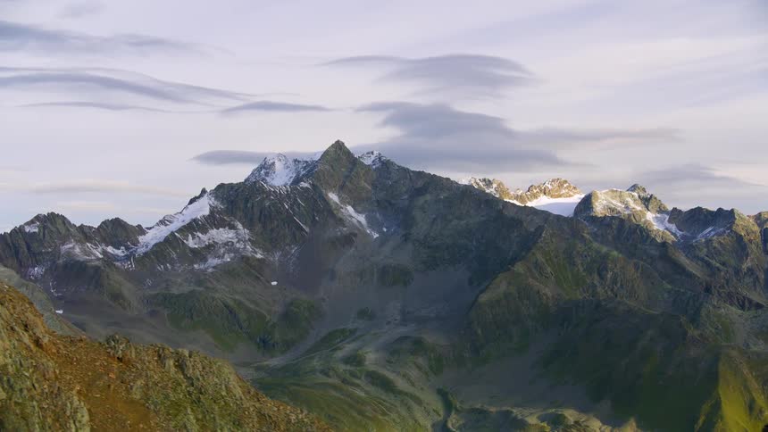 Aerial of rugged mountains separated by foggy valley on a cloudy day