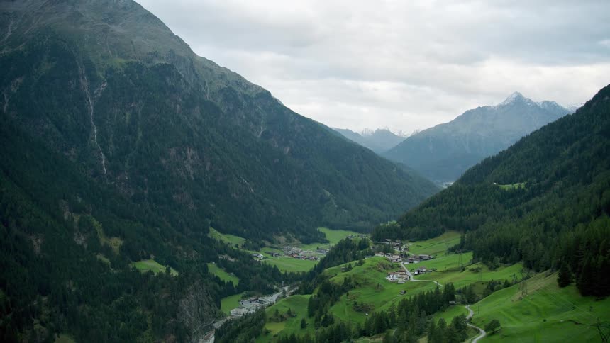 Aerial of dispersed houses near mountains at midday