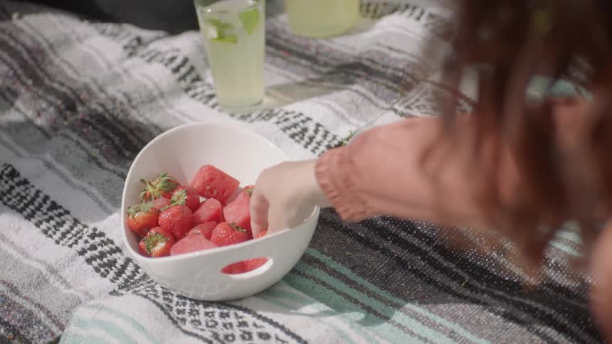 A person reaches for a piece of fruit from a bowl