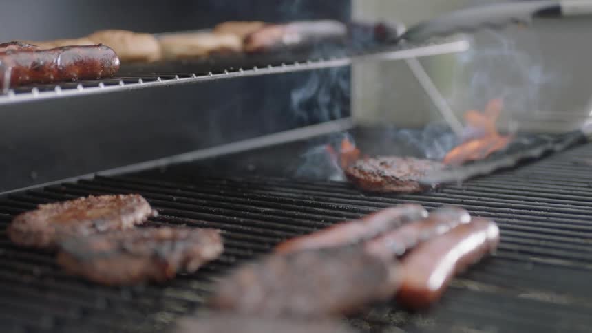 A person is flipping burgers on a grill